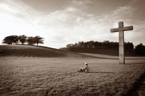 Man alone in a field with a cross