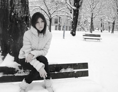 sad woman on park bench in snow